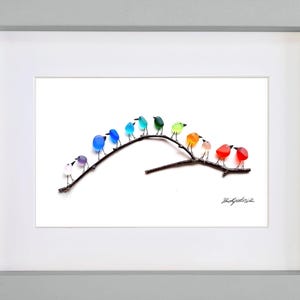 May include: A framed artwork featuring a collection of colorful glass birds perched on a dark brown branch. The birds are in various colors, including blue, green, orange, and red. The artwork is set against a white background and framed in a light gray frame.