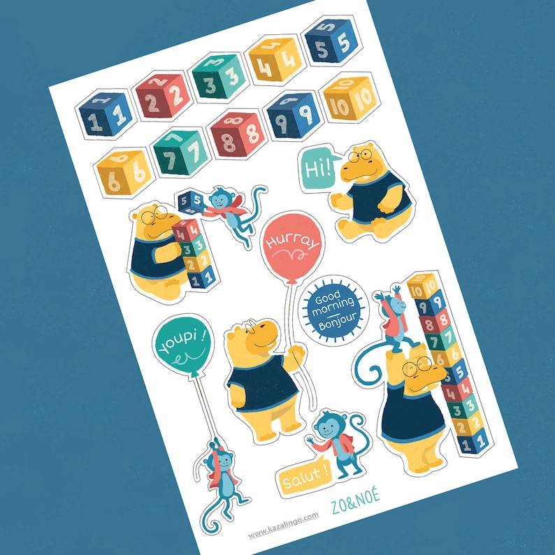 May include: A set of colourful stickers featuring animals, numbers, and phrases in French and English. The stickers include a hippopotamus, a monkey, and a bear. The numbers are displayed on blocks and a stack of blocks. The phrases include "Hurray", "Hi!", "Good morning Bonjour", "Youpi! er", and "Salut!"
