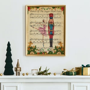 May include: A framed print of sheet music titled "Dance Of The Sugar Plum Fairy" featuring a ballerina and a nutcracker. The print is in a gold frame and is decorated with Christmas ornaments. A green Christmas tree and other holiday decorations are on the mantel.