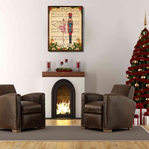 May include: A vintage-style Christmas print featuring a ballerina dancing with a Nutcracker soldier. The print is framed and hanging on a white wall above a fireplace with a lit fire. Two brown leather armchairs are positioned in front of the fireplace, and a decorated Christmas tree is in the background.
