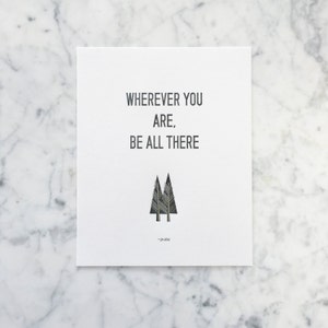 May include: A white card with black text that reads "Wherever you are, be all there" with a black and white illustration of two pine trees. The text "Jim Elliot" is written in smaller font below the trees.