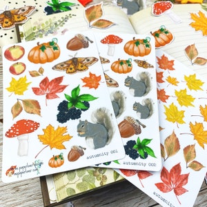 Puede incluir: Tres hojas de pegatinas con dise&ntilde;os oto&ntilde;ales. La primera hoja tiene una ardilla, bellotas, moras, setas, calabazas, hojas y una polilla. La segunda hoja tiene una ardilla, bellotas, moras, setas, calabazas, hojas y una polilla. La tercera hoja tiene una variedad de hojas en diferentes colores y formas. El texto en las hojas dice "autumity 001" y "autumity 002".