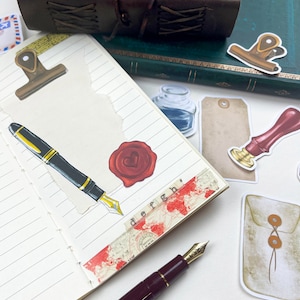 May include: A notebook with a variety of decorative stickers, including a wax seal, a pen, a bottle of ink, and a tag. The notebook has lined pages and a brown leather cover.