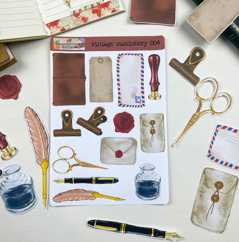 May include: Vintage stationery sticker sheet with images of envelopes, feathers, ink bottles, scissors, and a stamp. The sheet is white with a brown border and the text "vintage stationery 004" in black.