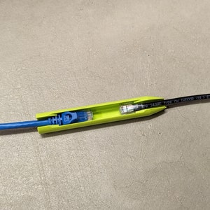 May include: A green cable management tool with a blue ethernet cable plugged in. The tool has the text "24AWG TYPE CM INDOOR 2UL1633" printed on it.