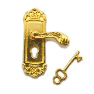 Könnte beinhalten: Vergoldeter Türknauf mit einem Schlüsselloch und einem passenden Schlüssel. Der Knauf hat ein verziertes Design und einen gebogenen Hebel.