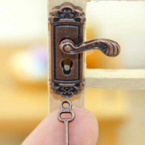 May include: A miniature antique-style door handle and key. The handle is made of metal and features a decorative design. The key is also made of metal and has a simple design.