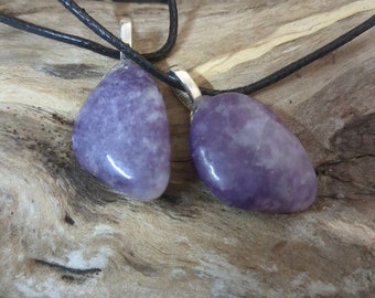 May include: Two purple amethyst stone pendants on a black cord necklace. The stones are teardrop shaped and have a natural, rough texture.