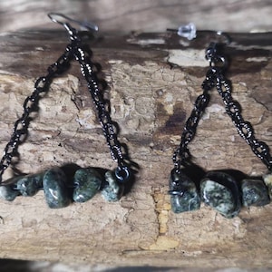 May include: A pair of dangle earrings with black chains and green and white stone accents.