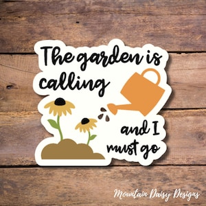May include: A white sticker with the text "The garden is calling and I must go" in black. There is a yellow watering can pouring water onto two yellow flowers with brown stems.