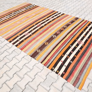 Può includere: Un tappeto a strisce colorate con un motivo geometrico. Il tappeto è in lana e ha un design tradizionale. È perfetto per aggiungere un tocco di colore e stile a qualsiasi stanza.