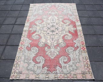 May include: Rectangular, vintage-style rug with a central red and cream medallion design. The rug features intricate patterns in shades of red, cream, gray, and hints of pink and green. The rug is placed on a dark gray tiled surface.