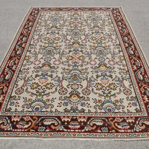 Può includere: Un tappeto color crema con un motivo floreale in tonalità di rosso, blu, verde e marrone. Il tappeto ha un bordo con un motivo paisley.
