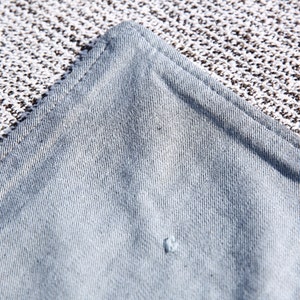 May include: Close-up of a light blue fabric with a subtle texture. The fabric has a slight sheen and appears to be woven.