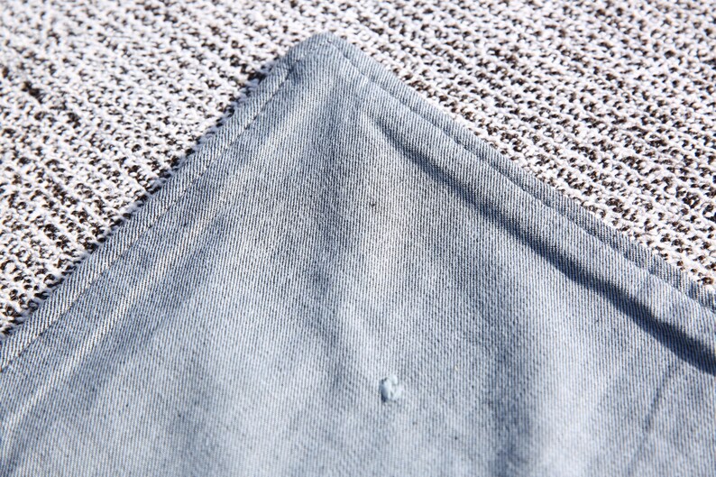May include: Close-up of a light blue fabric with a subtle texture. The fabric has a slight sheen and appears to be woven.