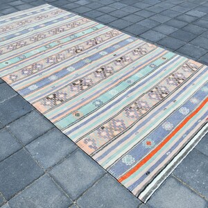 May include: A vintage striped rug with a muted color palette of pink, blue, and gray. The rug has a woven design with geometric patterns.