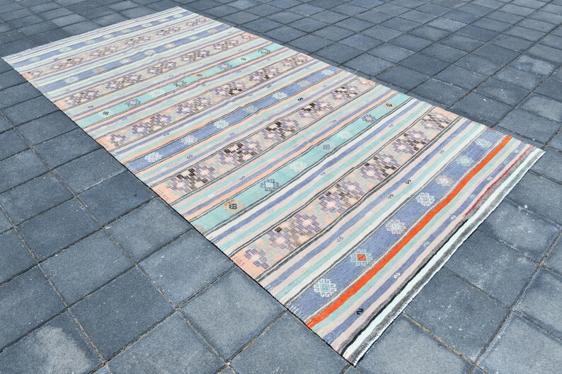 May include: A vintage striped rug with a muted color palette of pink, blue, and gray. The rug has a woven design with geometric patterns.