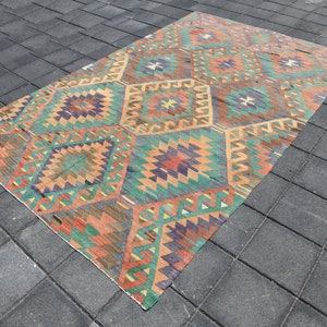 Pu&ograve; includere: Un tappeto vintage colorato con un motivo geometrico in tonalit&agrave; di rosso, arancione, verde, blu e marrone. Il tappeto ha un aspetto vissuto ed &egrave; fatto di lana.