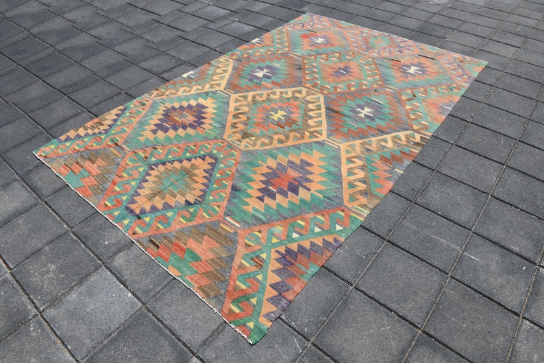 Pu&ograve; includere: Un tappeto vintage colorato con un motivo geometrico in tonalit&agrave; di rosso, arancione, verde, blu e marrone. Il tappeto ha un aspetto vissuto ed &egrave; fatto di lana.
