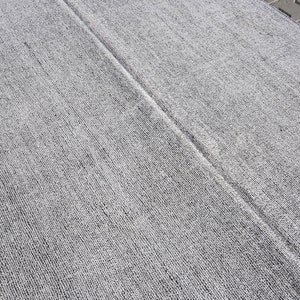 May include: A close-up of a gray and white textured rug with a subtle sheen. The rug has a woven appearance and is made of a soft, comfortable material.