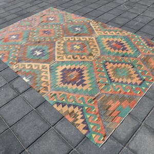 Pu&ograve; includere: Un tappeto vintage con un motivo geometrico in tonalit&agrave; arancio, verde, blu e marrone. Il tappeto ha un aspetto vissuto ed &egrave; fatto di lana.