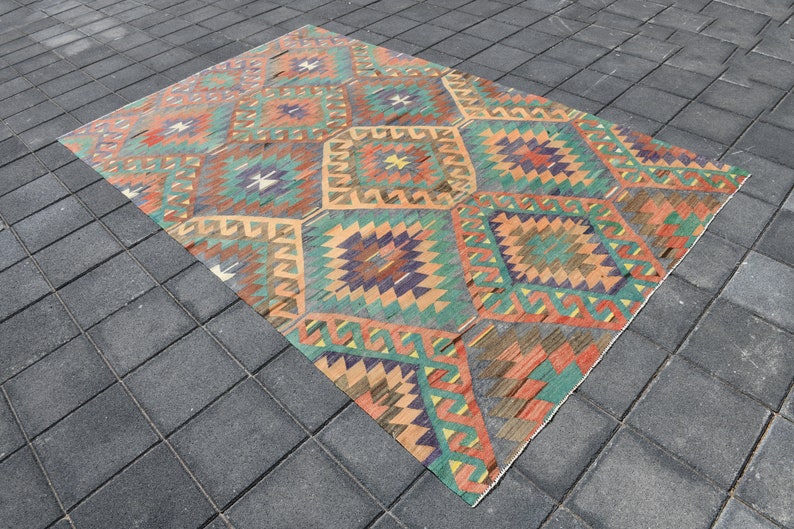 Pu&ograve; includere: Un tappeto vintage con un motivo geometrico in tonalit&agrave; arancio, verde, blu e marrone. Il tappeto ha un aspetto vissuto ed &egrave; fatto di lana.
