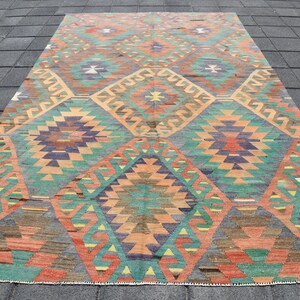 Pu&ograve; includere: Un tappeto vintage con un motivo geometrico in tonalit&agrave; arancio, verde, blu e marrone. Il tappeto ha un design a forma di diamante con dettagli intricati.