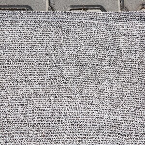May include: A close-up of a white and gray woven rug with a textured surface.