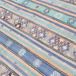May include: A striped rug with a geometric pattern in shades of blue, green, and peach.
