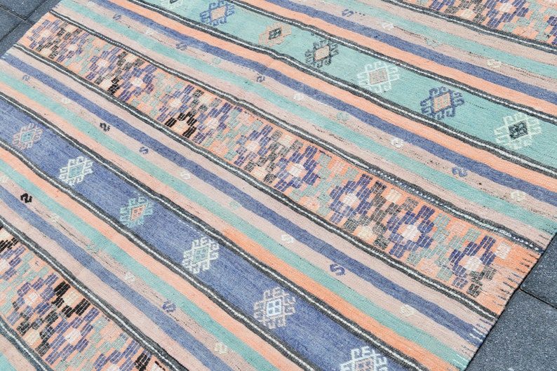 May include: A striped rug with a geometric pattern in shades of blue, green, and peach.