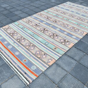 May include: A vintage striped rug with a muted color palette of light blue, pink, and orange. The rug has a geometric pattern with a subtle floral design.