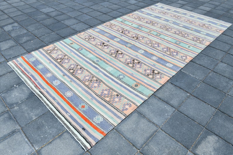 May include: A vintage striped rug with a muted color palette of light blue, pink, and orange. The rug has a geometric pattern with a subtle floral design.