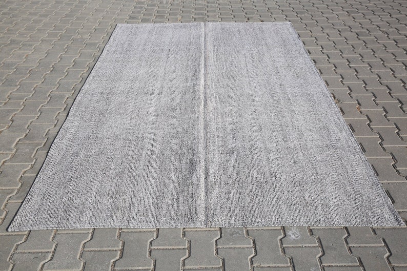 May include: A gray and white area rug with a subtle textured pattern. The rug is rectangular and has a center seam.