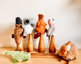 Puede incluir: Cinco marionetas de dedo de peluche de animales australianos en soportes de madera. Los animales son un koala, un ornitorrinco, un canguro, una cacatúa y un kiwi.