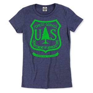 May include: A navy blue t-shirt with a green US Forest Service logo. The logo features a pine tree and the text "Forest Service", "US", "Department of Agriculture", and "Caring for the Land".