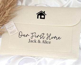 Pode incluir: Uma pasta de feltro branco com um ícone de casa preto e o texto "Our First Home Jack & Alice".
