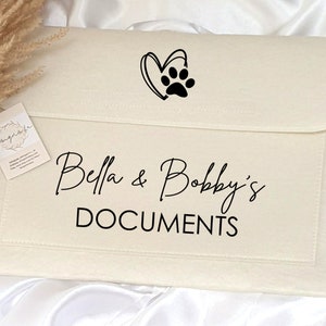 May include: A white canvas folder with a black paw print and heart design. The folder has the text "Bella & Bobby's DOCUMENTS" printed on it.