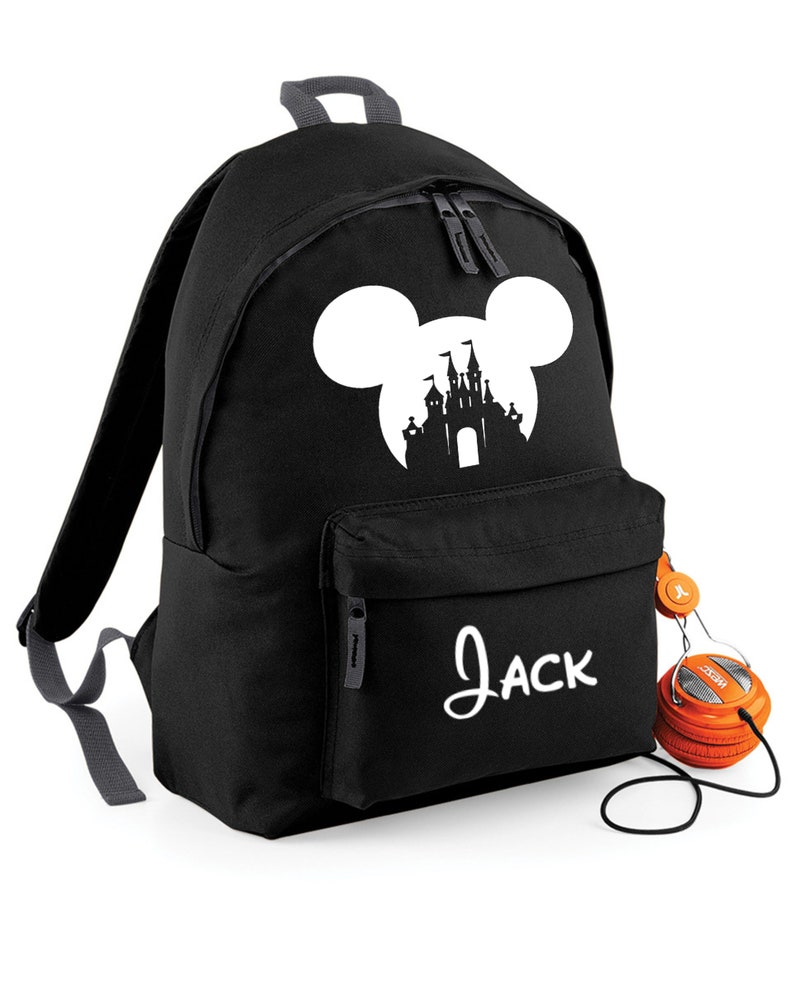 May include: Black backpack with a white silhouette of Mickey Mouse ears and a castle inside the ears. The backpack has a front pocket with the name "Jack" written in white.