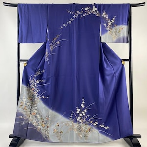 Puede incluir: Un kimono japonés tradicional con fondo azul y un patrón floral blanco. El kimono se muestra en un soporte.