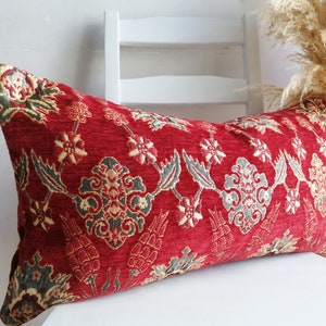 May include: Red and gray patterned lumbar pillow with a floral design. The pillow is made of a soft, textured fabric.