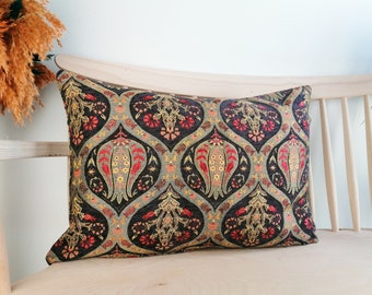 May include: A decorative pillow with a black background and a colorful floral pattern. The pattern features red, yellow, and green flowers and leaves. The pillow is made of a soft, textured fabric.