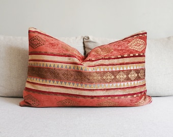 May include: A red, brown, and gold patterned throw pillow with a geometric design.