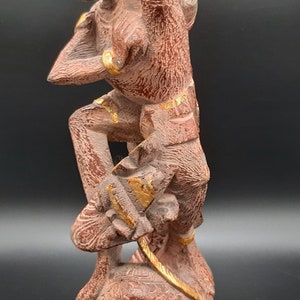 Könnte beinhalten: Eine handgeschnitzte Holzstatue einer mythischen Kreatur mit goldenen Akzenten. Die Kreatur steht auf einem Sockel und hat einen grimmigen Ausdruck.