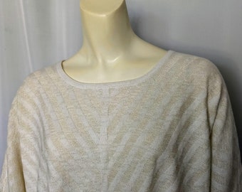 May include: A cream-colored sweater with a chevron pattern in a lighter shade of cream. The sweater has a round neckline and long sleeves. The fabric appears to be a lightweight knit.