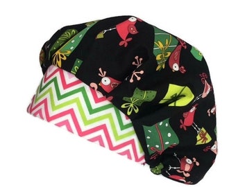 May include: A black scrub cap with a whimsical pattern of red birds and green gift boxes. The interior lining features a pink, white, and green chevron pattern. This cap is designed for medical professionals and is made of a soft, comfortable fabric.