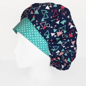 Op de afbeelding: Een blauwe en turquoise gepatenteerde chirurgische scrub-muts met een witte stippenrand. De muts is gemaakt van een zachte, comfortabele stof en is ontworpen om te worden gedragen door medische professionals.