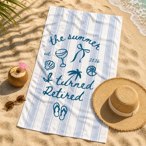 Pu&ograve; includere: Un telo mare rettangolare con strisce verticali azzurre e bianche. Al centro presenta una scritta blu scuro che recita the summer est. 2026 I turned Retired, accompagnata da icone grafiche di un bicchiere da cocktail, un fiocco, conchiglie, una palma e infradito.
