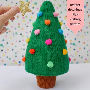 Puede incluir: Un árbol de Navidad tejido en verde con pompones coloridos. El árbol tiene una base tejida marrón. Una mano sostiene una estrella dorada. El texto en el lateral dice "Instant download PDF knitting pattern".
