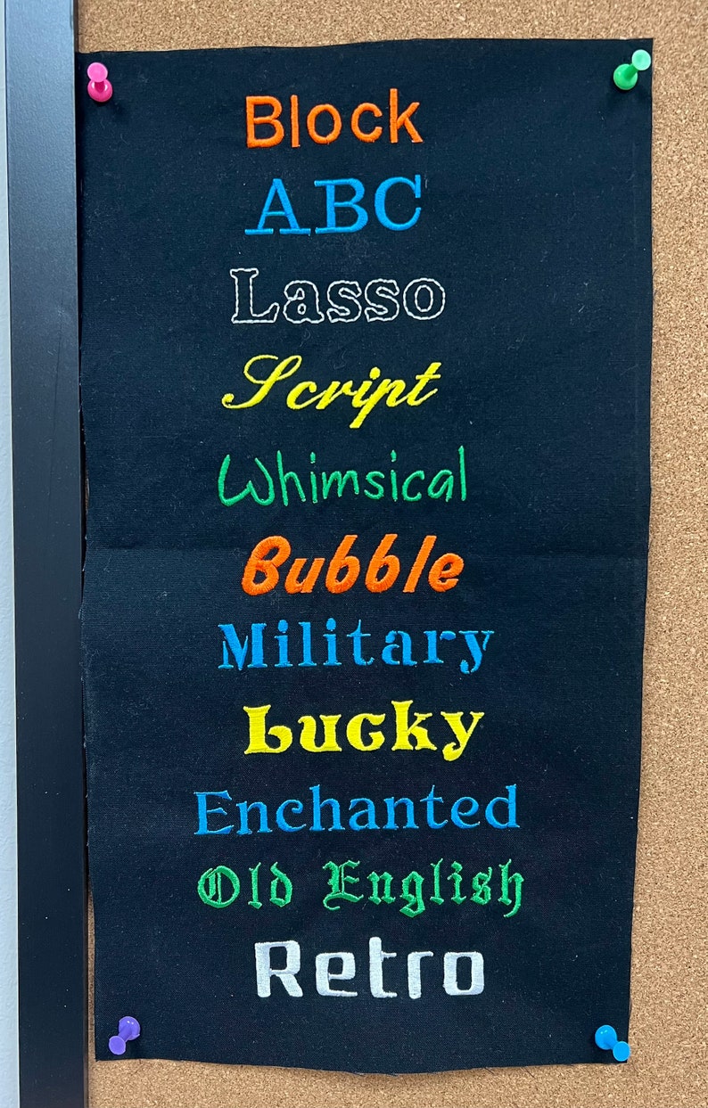 Op de afbeelding: Een zwarte stofstaal met verschillende borduurlettertypen in verschillende kleuren, waaronder "Block", "ABC", "Lasso", "Script", "Whimsical", "Bubble", "Military", "Lucky", "Enchanted", "Old English" en "Retro".