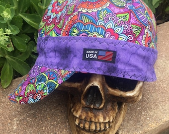 May include: A purple and multi-colored paisley patterned welding cap with a purple brim and a "Made in USA" label.